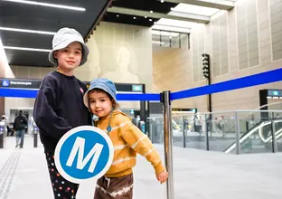 two kids holding the M logo at the City stations opening