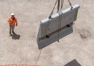 A construction worker is signalling a cement barrier 