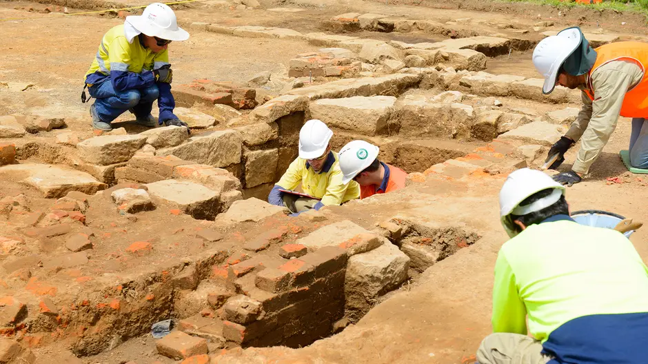 Five construction workers inspecting the ground for archaeological artefacts during the excavation at Sydney Metro's White Hart Inn site.