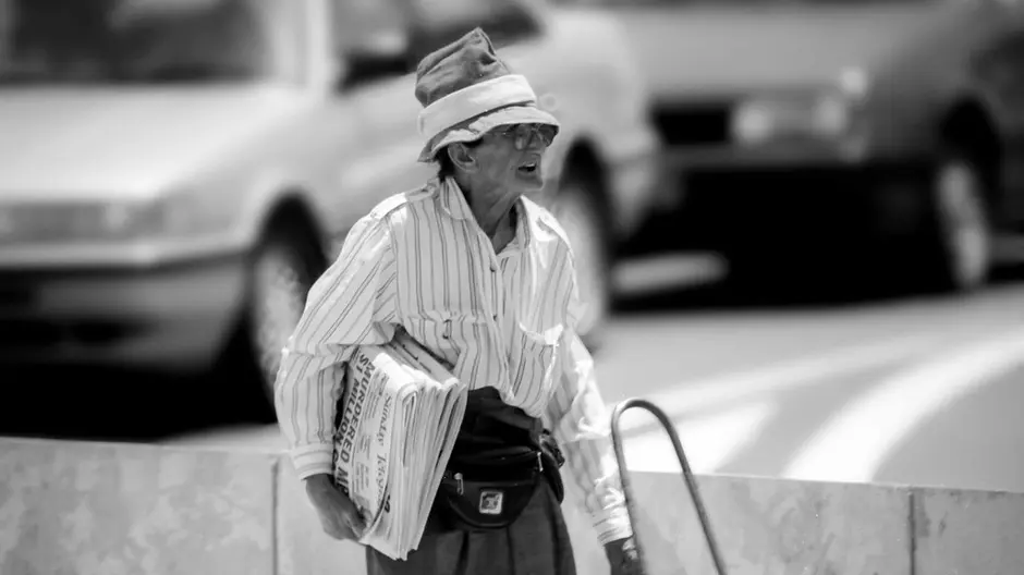 Beatrice Bush standing with a pile of newspapers to sell 