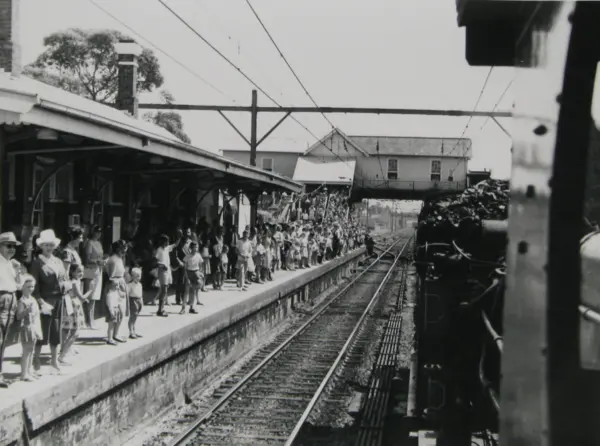 A black and white photo of commuters waiting at the platform as a steam train arrives at Chatswood Railway Station during Willoughby Centenary celebrations in 1965.