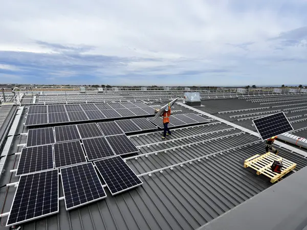 An arial view of two construction workers lifting solar panels into place at a Sydney Metro site. 