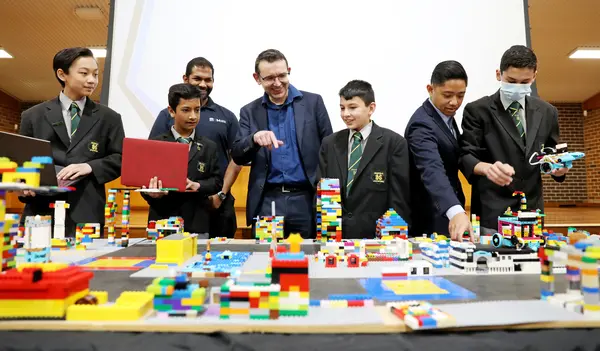 A group of 5 students showing their Lego display to two teachers at the teacher development day at 2022 Granville High School