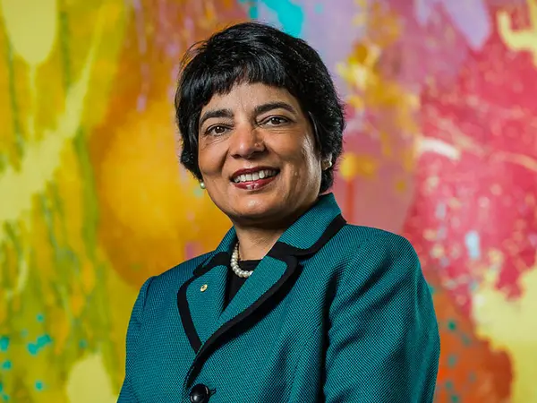 Dr Marlene Kanga standing infront of a colorful background, smiling at the camera