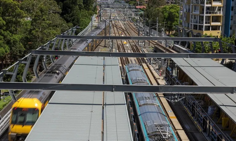 An arial shot looking down on the station platform as a Sydney Metro Train arrives at the platform next to a Sydney Trains train at Chatswood Station. 