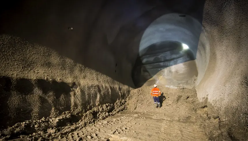 An on the ground view from inside the cavern as a construction worker inspecting the tunnel with their head torch shining a light to the top of the tunnel as tunnelling commences at Sydney Metro's Pitt Street North Castlereagh Cavern site.