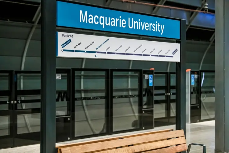 A close up shot of the signage displayed on the platform behind the screen safety doors above a bench at Sydney Metro's Macquarie University.