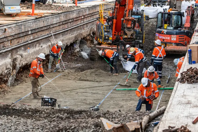 Construction workers in high viz working on reinforcing the railway track which is above the future central walk