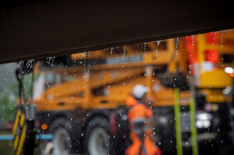 Image of rain falling with blurred out-of-focus heavy machinery in the background.