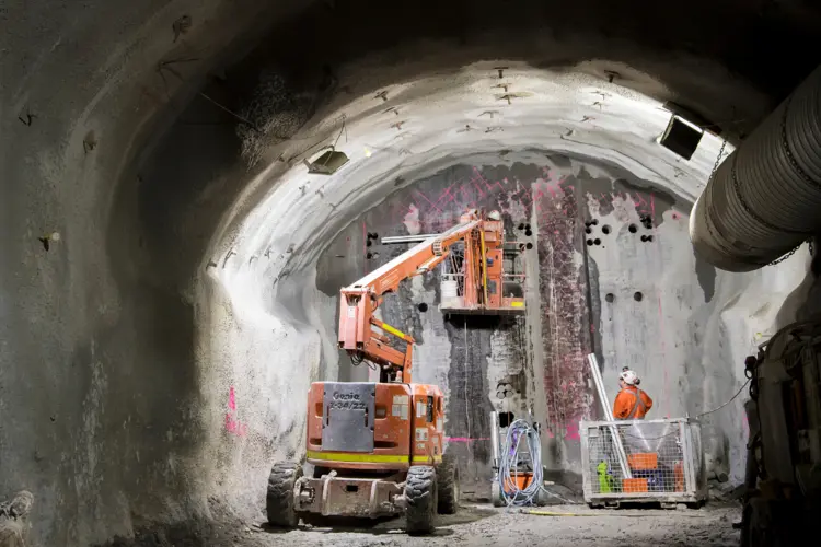 A construction worker is inside the Central Station tunnel construction site on top of a cherry picker looking at the end of the tunnel.