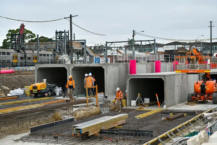 Construction workers in full personal protection equipment work on the aqueduct construction site at Sydenham.