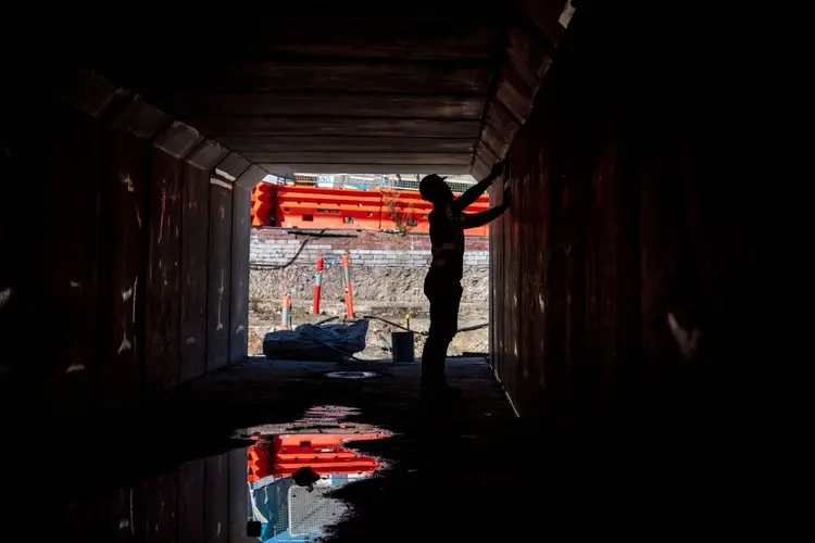 An on the ground view looking at a construction worker inside a tunnel