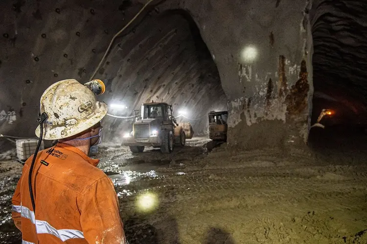 A view from behind a construction worker in orange high-vis looking at the work being completed inside Barangaroo Crossover cavern.