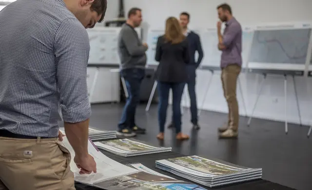 A man looks at a brochure at a community event in Bankstown while a group of people have a conversation in the background.