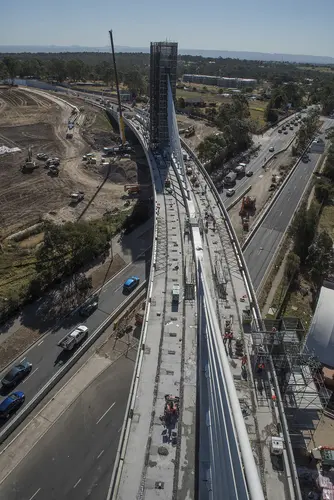 A bird's eye view of Sydney Metro's Windsor Road bridge being constructed, there are cars traveling on the road below.