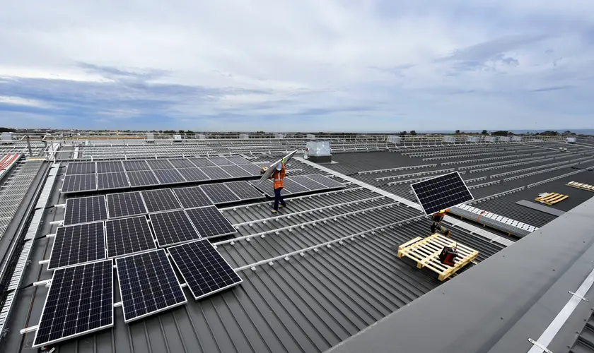 An arial view of two construction workers lifting solar panels into place at a Sydney Metro site. 