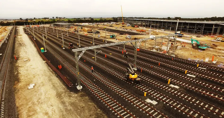 An arial view looking down at the ten tracks being laid at the Sydney Metro Train Facility at Rouse Hill with construction happening in the background.