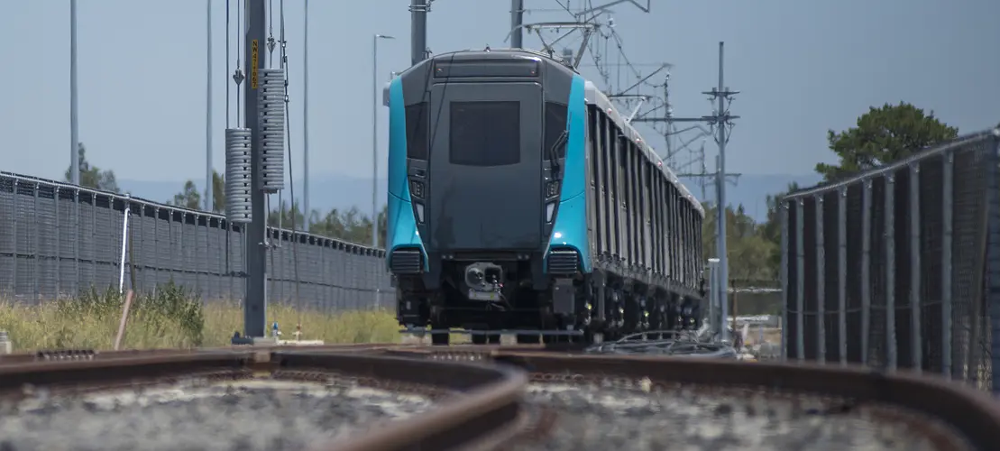 An on the ground shot looking at a Sydney Metro train coming towards the camera being tested along the tracks.