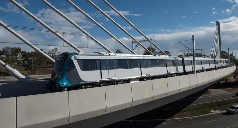 An arial view looking directly across a Sydney Metro train being tested on the completed tracks at Windsor Road Bridge. 