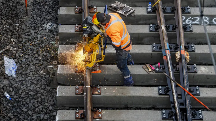 Sparks fly as construction workers use a grinder on the metal tracks at Bankstown Station.