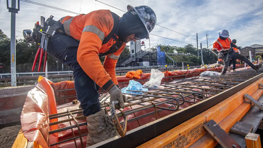 A close up view of a construction worker laying metal rods in place on site at Dulwich Hill Station.