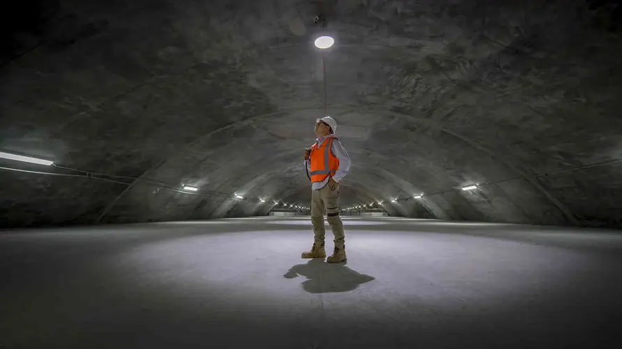 On the ground image of a construction worker looking up inside the cavern in Sydney Metro's Barangaroo Station. 