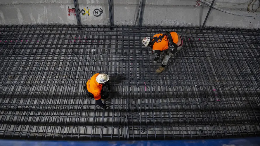 Two construction workers assemble the track slab steel reinforcement works at Pitt Street Station cavern.