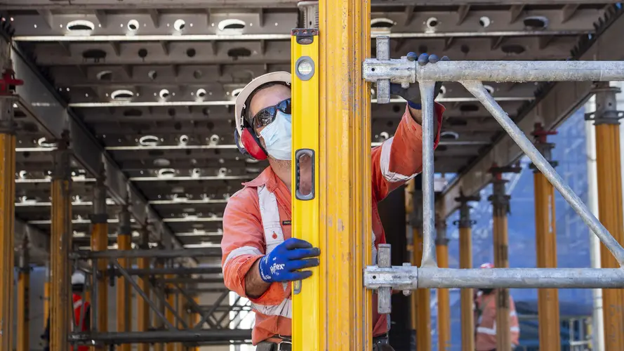 A construction worker is vertically leveling a steel beam at Waterloo Station.