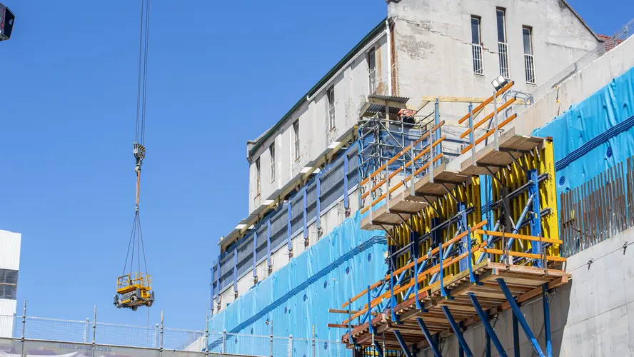 A large tower crane on Waterloo Station construction site is lifting material into the station box.