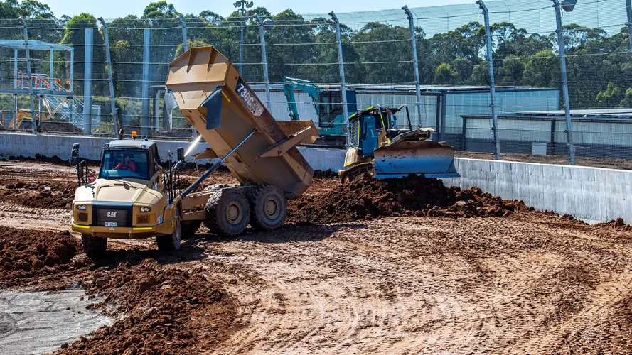 A dump truck unloads dirt at the construction site of the new Sydney International Speedway.