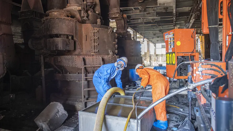 Two construction workers working at White Bay Power Station in full PPE suits