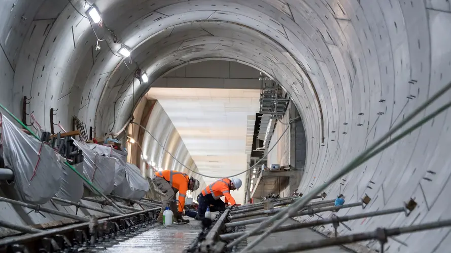 On the ground view of construction workers laying the final track down in the underground tunnel at Sydney Metro's between Central and Pitt Street stations.