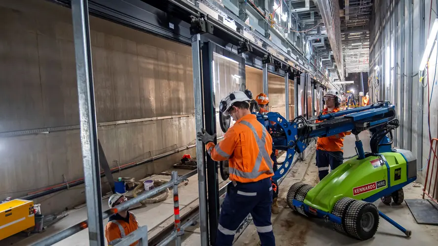 Construction workers and machinery used to install platform screen doors at Sydney Metro's Waterloo Station