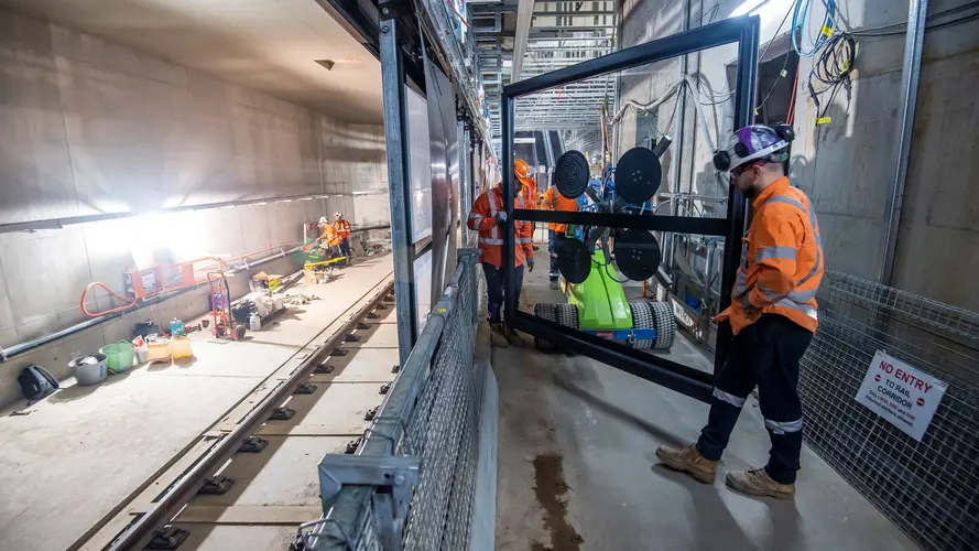 Construction workers installing platform screen doors at Sydney Metro's Waterloo Station