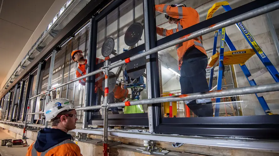 Construction workers installing platform screen doors at Sydney Metro's Waterloo Station