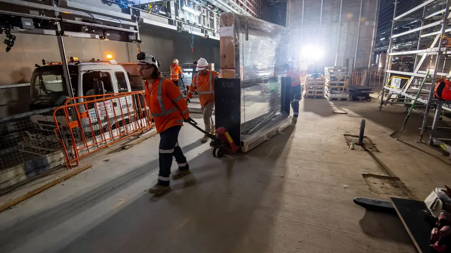 Construction workers delivering a platform screen door through a construction site