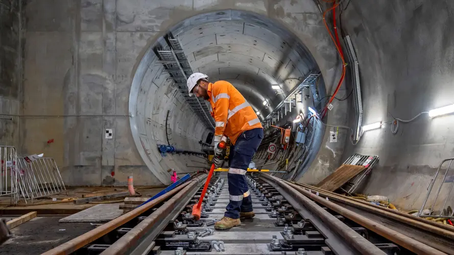 Construction worker building skeleton track in underground crossover cavern