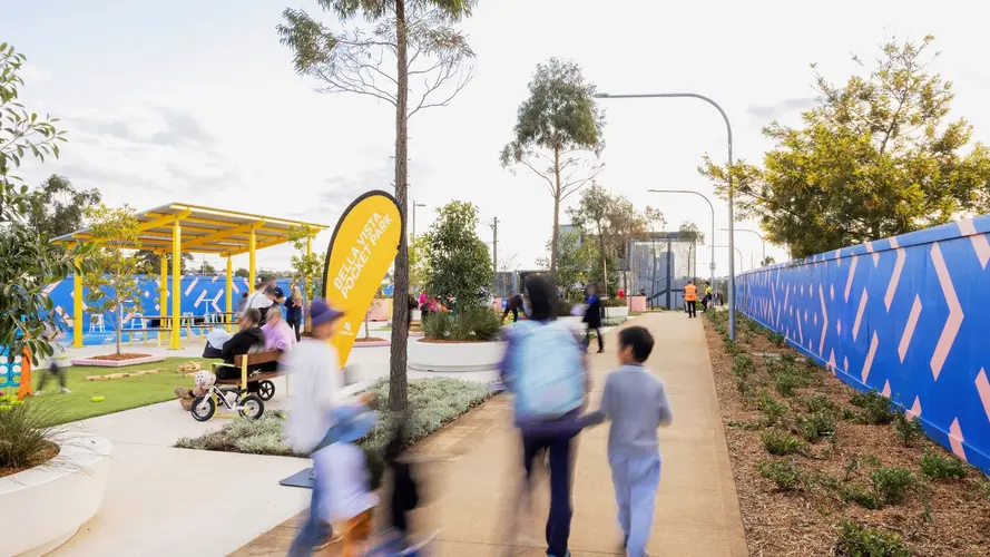 Photo of Bella Vista Pocket Park with blurred out profiles of people walking down a path.