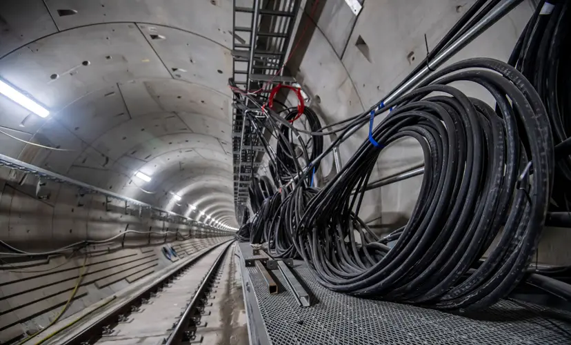 An on the ground shot looking through the lit up tunnel with power cables on the side 