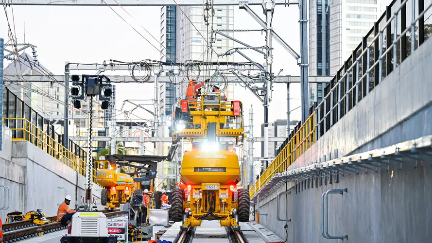 An on the ground view Construction workers on a some heavy machinery completing overhead track work at the Northern Connection 