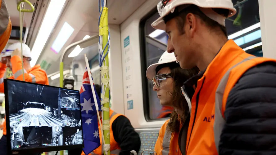 Two engineers watch a computer screen on a metro train as testing commences for CIty & Southwest.