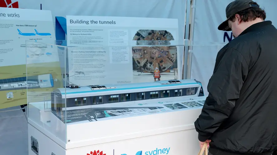 A man at a Sydney Metro stall looking a Metro train model