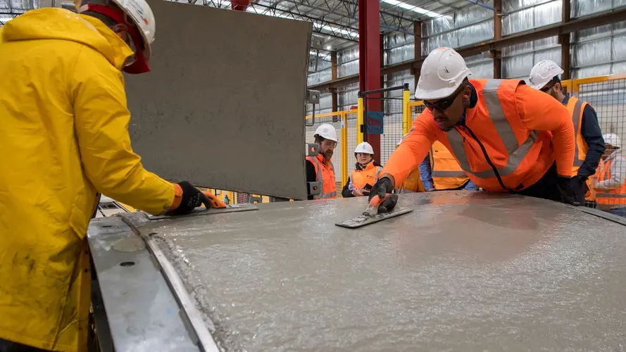 2 workers are pouring cement to produce a precast segment