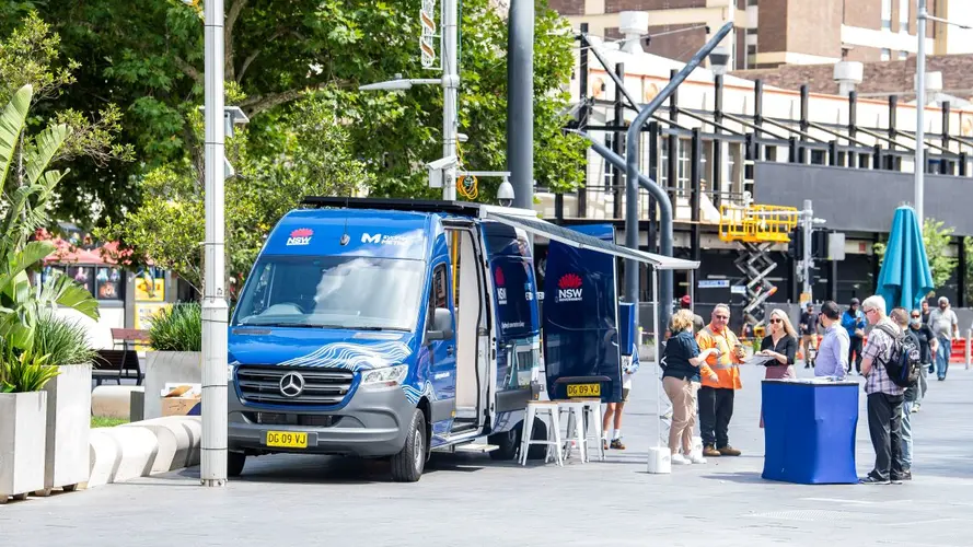 Blue Sydney Metro van on the road with a table set in front to attend visitors 