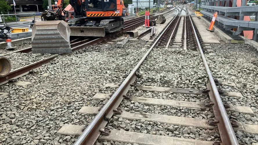 A rail line is under construction with workers working at the end 