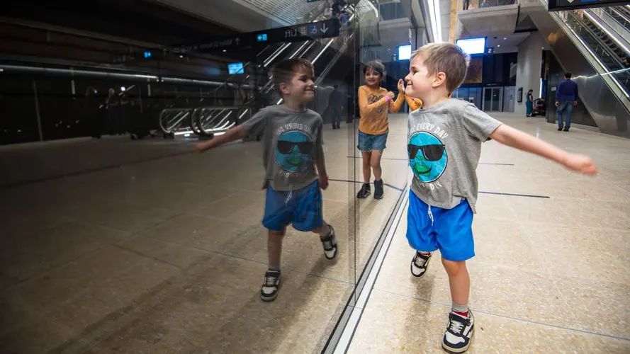 Young boy walking past the metro gates smiling