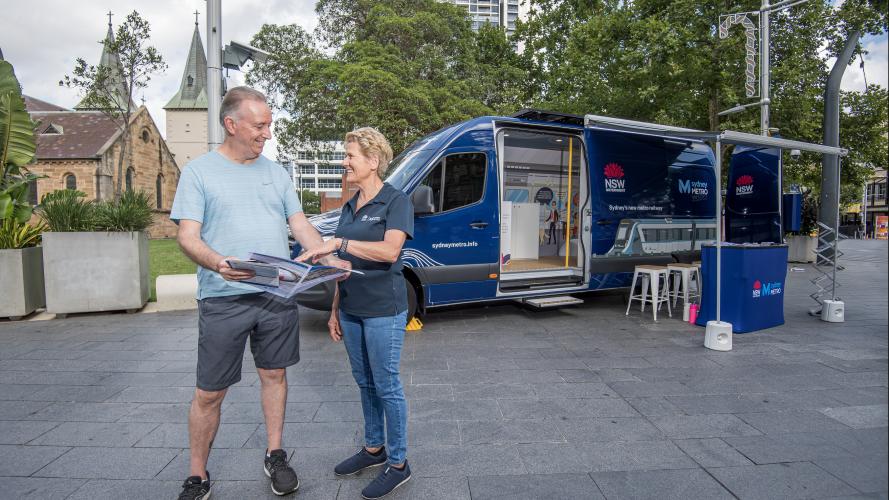 Sydney Metro worker talking to a member of the community in front of the Sydney Metro van