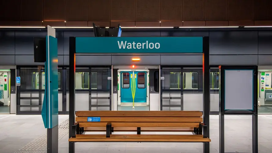 Waterloo Station sign on the platform with platform screen doors open behind it, opening to a Metro train