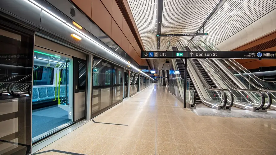 Sydney Metro station platform showing Metro train pulled in with platform screen doors open and also the escalators leaving the platform