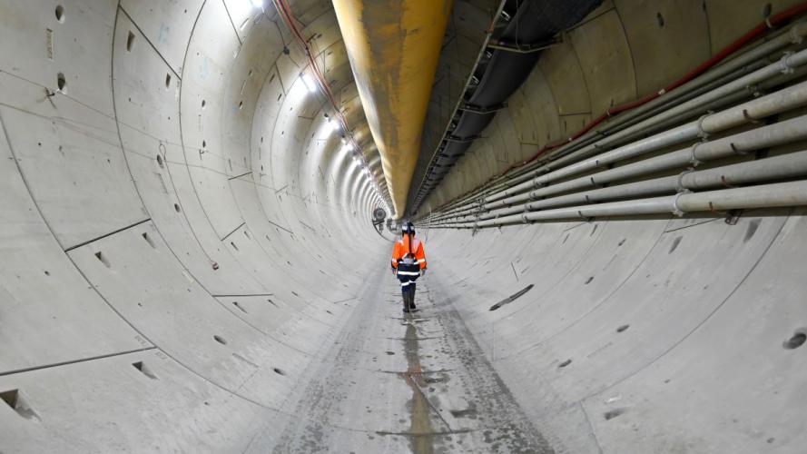 Worker in hi-vis gear walking through a tunnel
